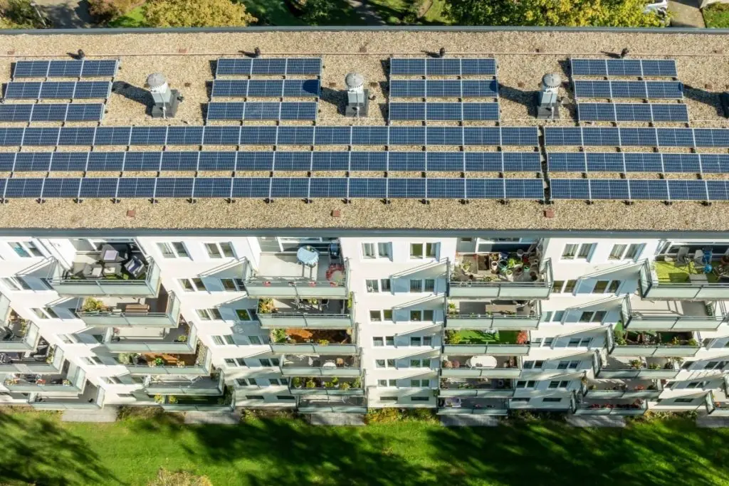 Wohnblock mit Solaranlage auf dem Flachdach, Balkonen und Grünfläche