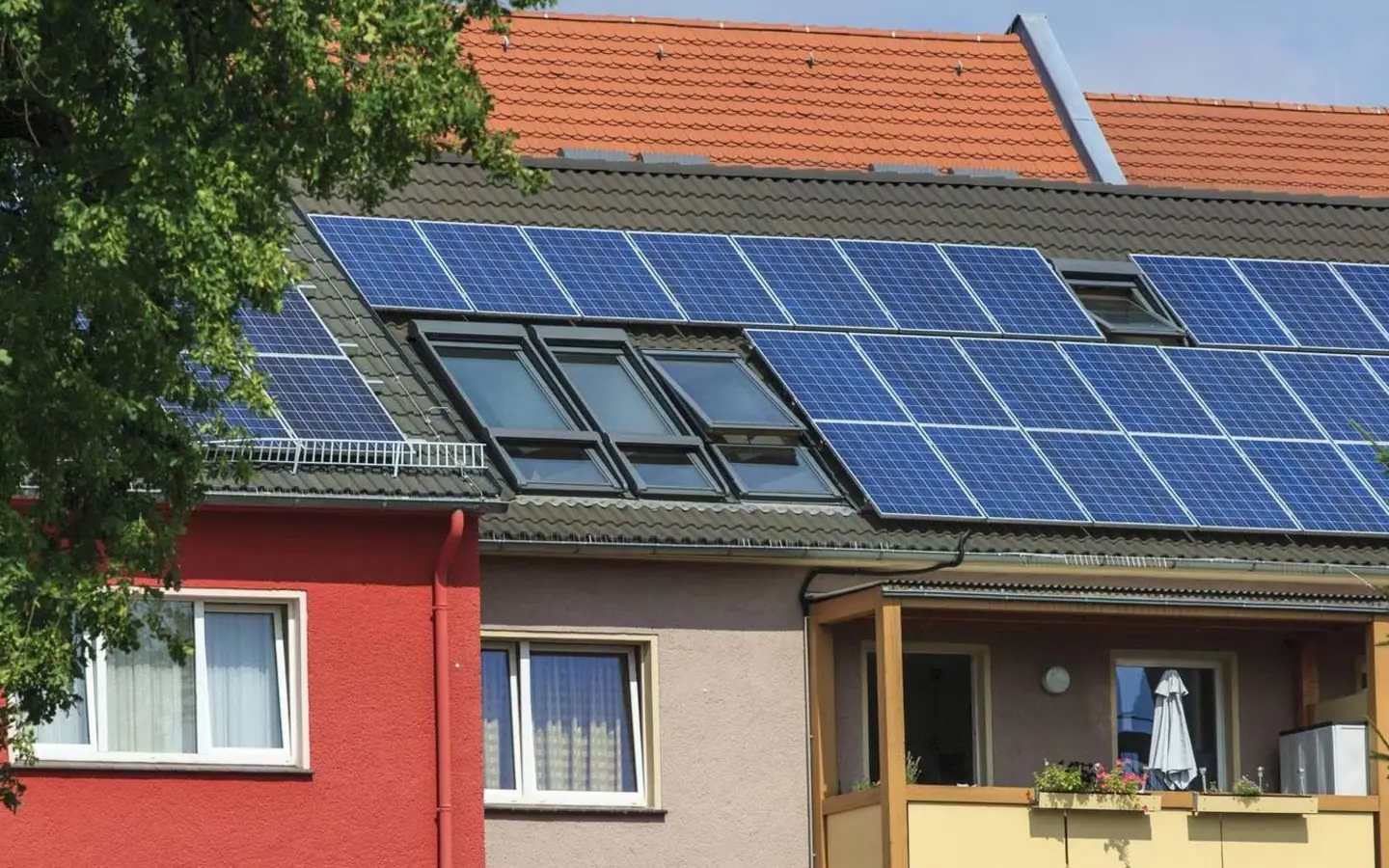 Mehrfamilienhäuser mit Solarmodulen auf dem Dach und Balkonen im Sommer
