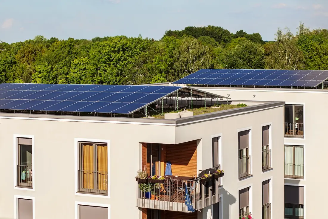 Mehrfamilienhaus mit Solaranlage auf dem Flachdach und bepflanztem Balkon